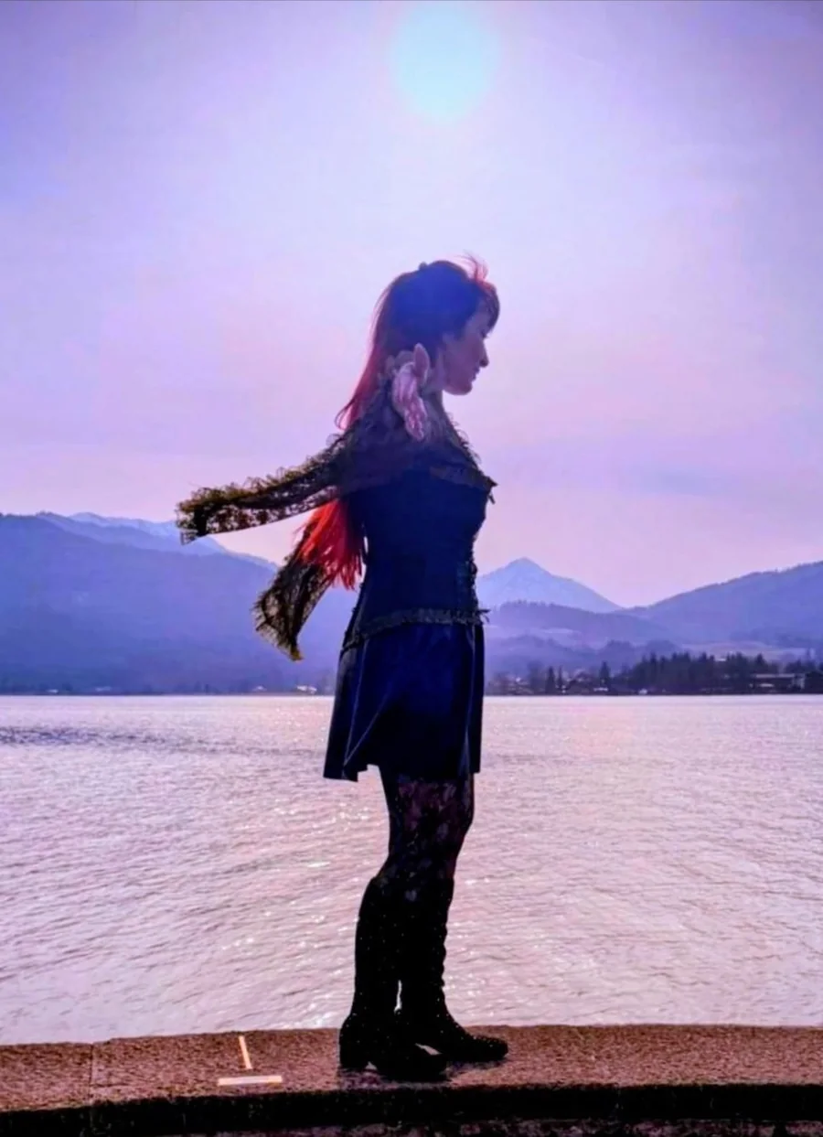 Katharina in der violetten Dämmerung am See, die Arme weit ausgestreckt